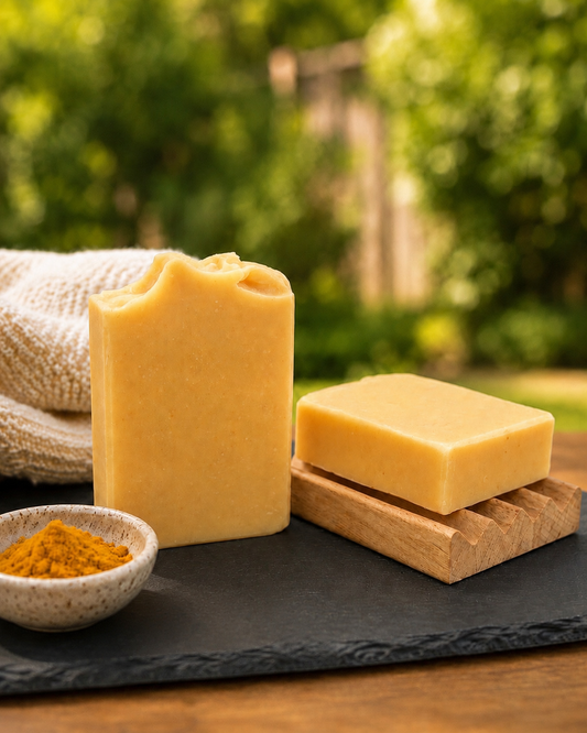 Turmeric Brightening Bar soap bars with turmeric powder on slate board, green garden background